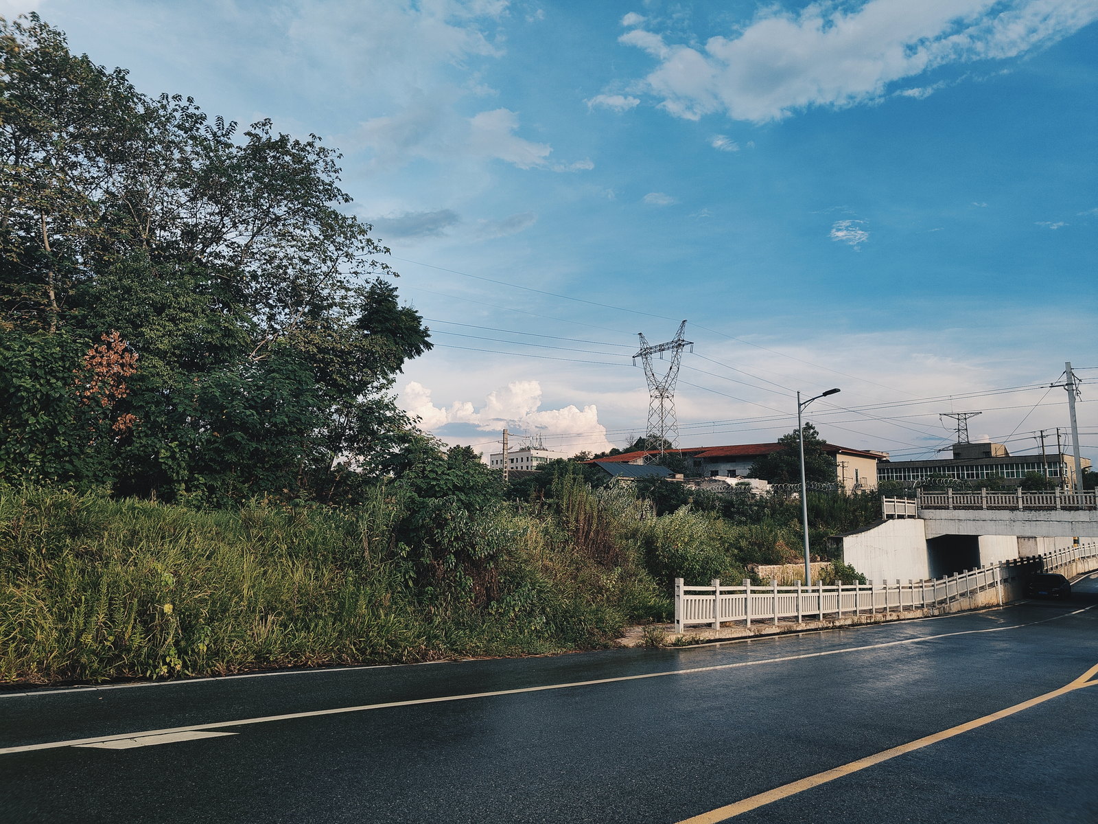 蓝天白云下的公路与远处电塔