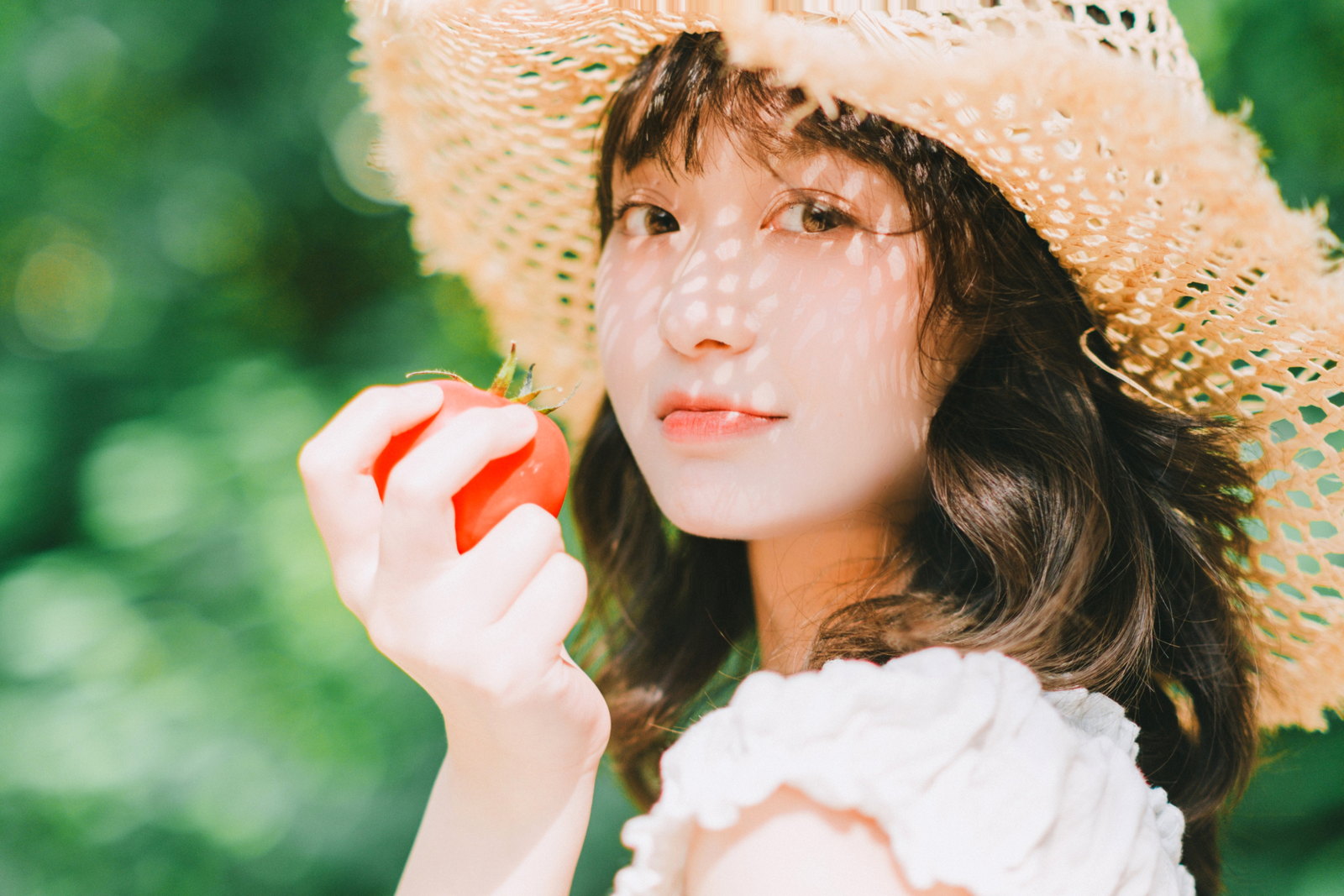 戴草帽的女子拿着苹果看向镜头