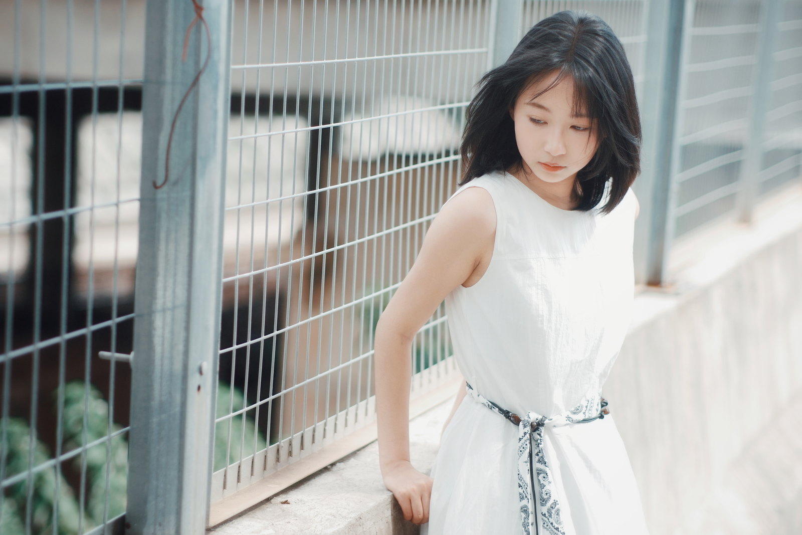 白色上衣的女子站在金属网旁